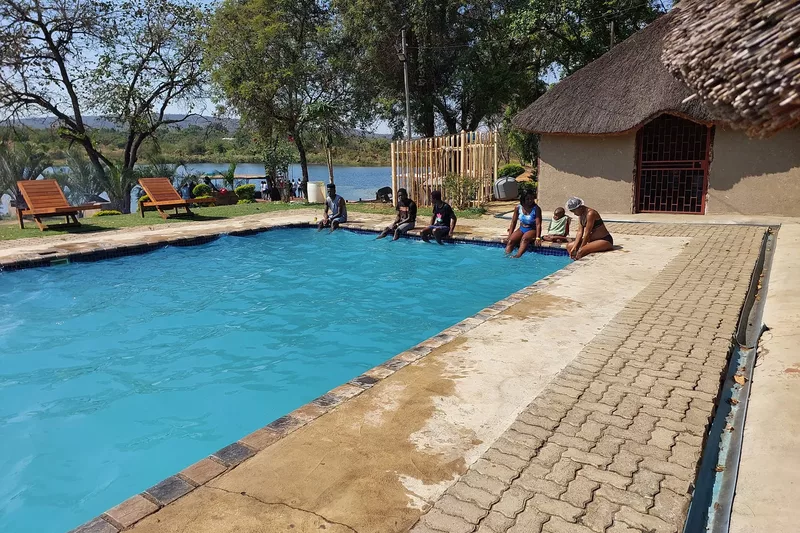 Tourists sitting on the edge of the a swimming pool at Refilwe Farm Resort in Tzaneen