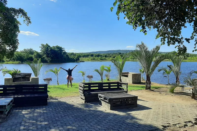 Tourist raising hands facing the dam with wooden chairs behind her at Refilwe Farm Resort in Tzaneen