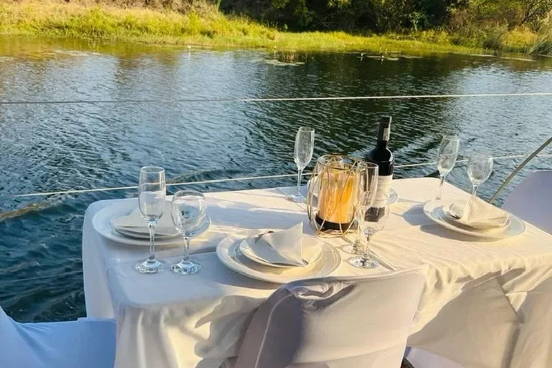 Dining table set up with white tablecloth a bottle of wine and wine glasses in a boat at Refilwe Farm Resort in Tzaneen